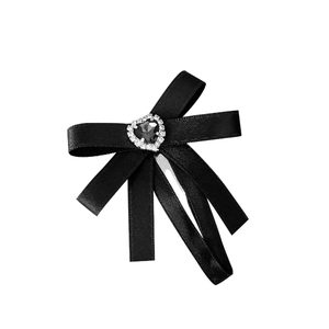 Pince à cheveux noeud en satin noir avec centre en strass en forme de coeur sur fond blanc