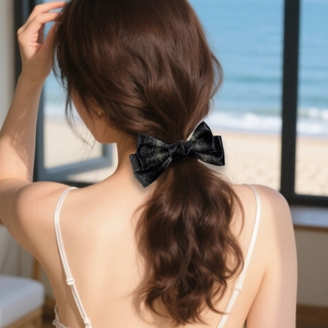 Elegant black glitter bow hair clip shown on model for a sophisticated back hairstyles