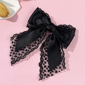 Elegant black lace bow hair clip crafted with satin material on a pink background