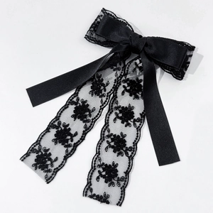 Détail de la broderie en dentelle et du nœud en satin noir de cette barrette élégante