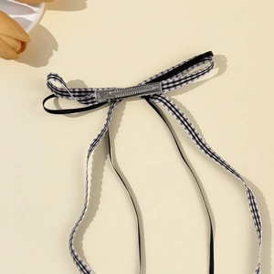 Detail of plaid bow hair clip with long ribbons and metal duckbill attachment