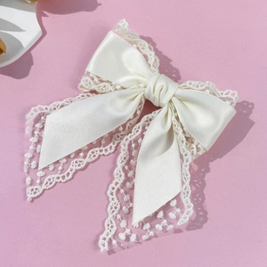 Close-up detail of cream white satin and floral lace double layered bow hair clip