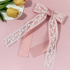 Detalle del lazo rosa para el cabello con encaje blanco y cintas largas de seda