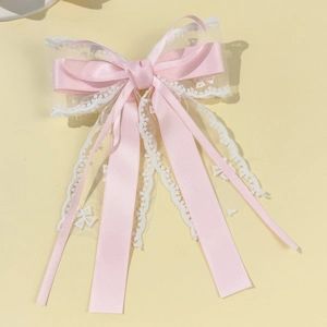 Dettaglio del fermaglio per capelli con fiocco in raso rosa e pizzo bianco a nastri