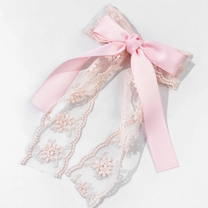 Barrette nœud en satin rose avec rubans en dentelle florale sur fond blanc pur