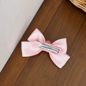 Détail du dos d'une pince à cheveux en satin rose avec clip métallique argenté robuste