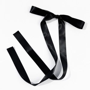 Close-up of elegant black satin ribbon hair clip with long streamers on white background