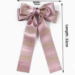 Detail showing a 13x22cm champagne pink bow hair clip with gold sparkles and long ribbons
