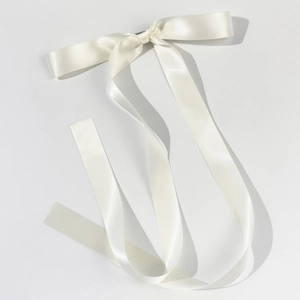 Detail showing the elegant ivory satin ribbon hair clip with high-gloss smooth texture