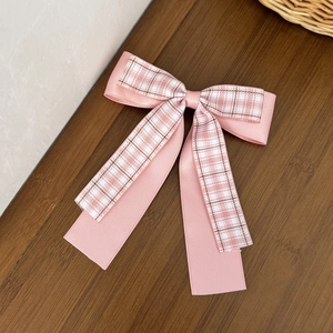 Pink plaid double-layered bow hair clip with long ribbons on a dark wooden background