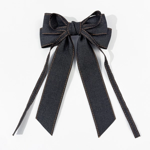 Détail du nœud en denim bleu foncé avec coutures orange et rubans longs élégants
