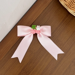 Barrette nœud en satin rose avec breloque cerise et lapin sur bois sombre