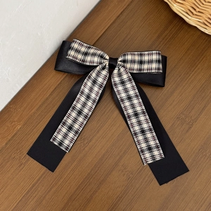 Detail of plaid double-layer bow hair clip with black satin ribbons and fabric texture