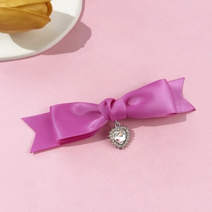 Dettaglio di un fermaglio a fiocco in raso viola con pendente a cuore in strass lucido
