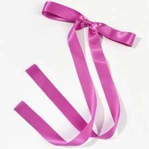Detail of rose pink satin bow hair clip with long flowing ribbons on white background