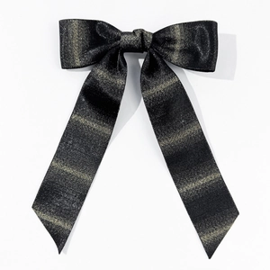 Close-up of large black bow hair clip with elegant golden metallic stripes and fine texture