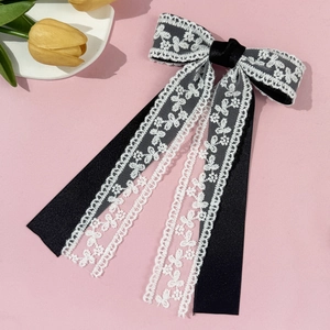Detalle de un elegante lazo para el pelo en satén negro y encaje blanco con cintas largas