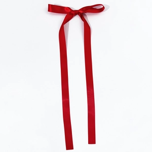 Detail of red satin ribbon bow hair clip with long streamers on white background