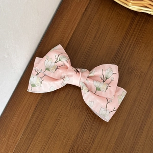 Detailaufnahme einer rosa Haarklammer mit Blumenmuster und eleganter Magnolien-Schleife