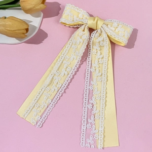 Detalle de la pinza para el pelo con lazo de satén amarillo claro y encaje blanco