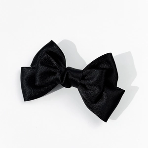Close-up of black satin bow brooch with elegant ribbon texture and pearl detail