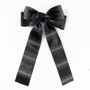 Detail of elegant black ribbon bow hair clip featuring golden glitter stripe patterns