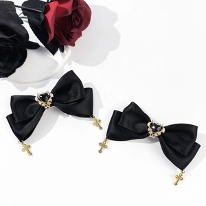 Detailed shot of black satin bow hair clips with gold crosses and heart gemstone