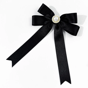 Close-up of black satin ribbon brooch with an elegant pearl center and gold trim