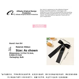 Detail view of a black ribbon bow hair clip with a metallic heart cross pendant