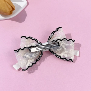 Detail view of lace bow hair clip with black scalloped edges and a silver duckbill base