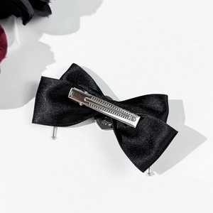 Gothic black satin bow hair clip with silver heart buckle on a white background