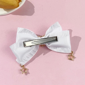 Détail de la pince à cheveux nœud en satin blanc avec breloques étoiles dorées