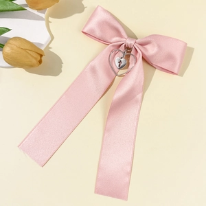 Close-up of pink satin bow hair clip with silver hollow heart and cross pendant