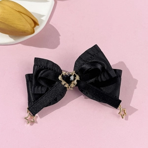 Vue détaillée du nœud papillon en satin noir avec gemme cœur et étoiles dorées