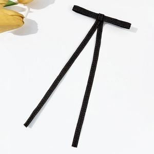 Black denim bow hair clip with brown stitching on a clean white background