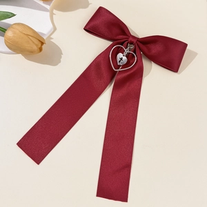 Close-up of deep red satin bow hair clip with silver heart and cross pendant decoration