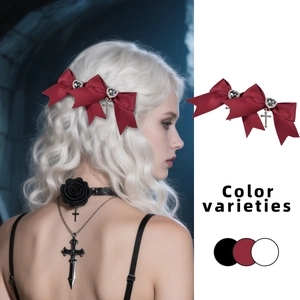 Detail of red satin bow hair clip with silver heart rhinestone and cross pendant charm