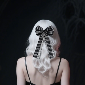 Detail of a black Gothic lace bow hair clip with white text on silver wavy hair