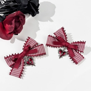 Detail of red checkered bow hair clips with silver gothic heart cross pendants