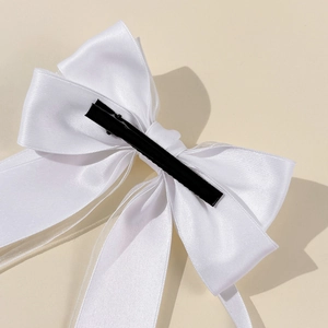 Détail de l'arrière d'un nœud papillon en satin blanc avec sa barrette en métal noir durable