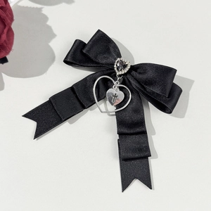 Détail de la barrette à nœud en satin noir avec gemme cœur et pendentif croix