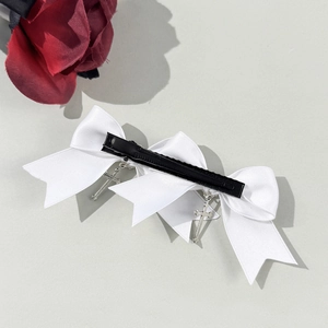 Gothic white ribbon bow hair clip with silver cross pendants on a grey background
