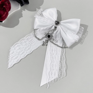 Détail du nœud en dentelle blanche avec gemme cœur noire, chaînes argentées et croix
