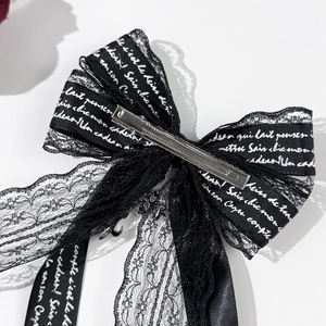Macro shot of black lace bow hair clip with silver metal duckbill clip and ribbon detail