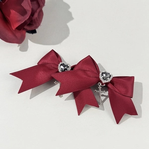 Macro shot of gothic wine red bow hair clips with silver cross pendant and heart rhinestone
