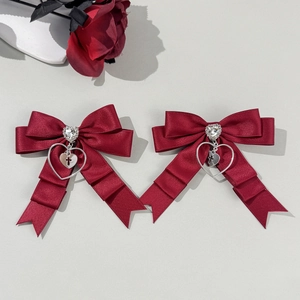 Détail de nœuds en soie bordeaux avec strass en cœur et pendentif croix