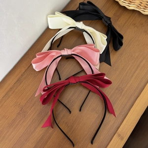 Serre-têtes élégants avec nœuds en satin noir, crème, rose et bordeaux sur bois