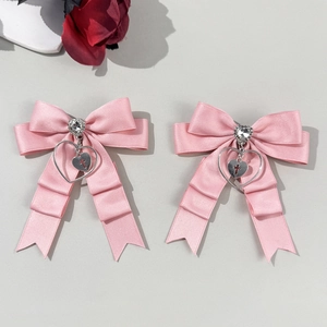 Détail de barrettes à nœuds roses gothiques avec pendentifs en métal cœur et croix