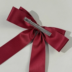 Detail of the silver metal alligator clip on a burgundy satin bow hair clip