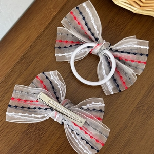 Rainbow ribbon bow hair tie and clip set with stripe pattern on wooden background